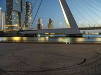 a large bridge that spans across the water and to the surrounding buildings and a park bench at the end