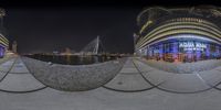 a fish eye view of city from the boardwalk area at night, and a reflection of a harbor and ferris wheel in the foreground