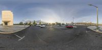 a street corner with cars parked in the front and buildings on the back side and an empty parking lot