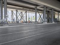 the view of the city under a highway with bikes parked on it, on the road side and on the street