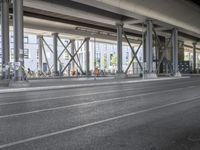 the view of the city under a highway with bikes parked on it, on the road side and on the street