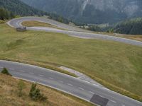 there are two motorcycles riding on a winding mountain road on a cloudy day in europe