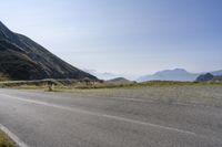 a motorcycle parked at the side of a mountain road on a sunny day with a horse