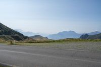 a motorcycle parked at the side of a mountain road on a sunny day with a horse