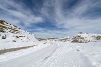 a large snowy area next to a road with tracks in it and mountains in the distance