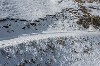 the two men are skiing in the snow next to a rocky trail, and rocks