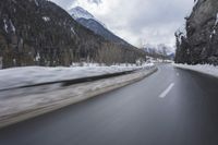 a curve of road in the mountains is almost empty during winter with snow covering the ground and trees
