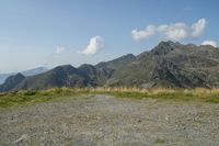 a stop sign is placed in a rocky area, with mountains in the distance behind