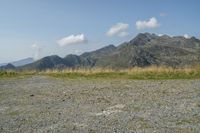 a stop sign is placed in a rocky area, with mountains in the distance behind