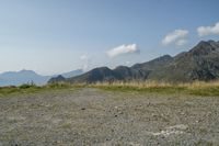 a stop sign is placed in a rocky area, with mountains in the distance behind