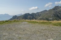 a stop sign is placed in a rocky area, with mountains in the distance behind