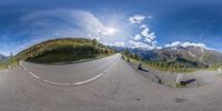 a fish eye view looking down the mountain road, with a view of the mountain range through the lens