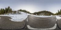 this is a fisheye shot of a road in the middle of the mountains and trees