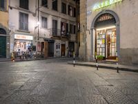 a person walking in a sidewalk at night in an urban area with cobblestones