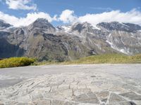 a yellow skate board sitting on top of a cobblestone road under mountains in the background