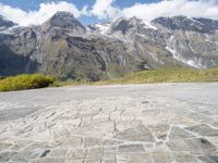 a yellow skate board sitting on top of a cobblestone road under mountains in the background