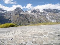 a yellow skate board sitting on top of a cobblestone road under mountains in the background