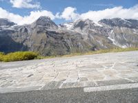 a yellow skate board sitting on top of a cobblestone road under mountains in the background