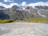 a yellow skate board sitting on top of a cobblestone road under mountains in the background