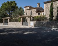 a large house with stone and stucco walls and a fence that extends the front yard