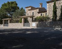 a large house with stone and stucco walls and a fence that extends the front yard