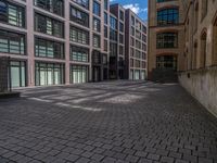 a brick courtyard has steps leading up to it, and a blue umbrella is on the ground