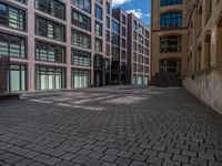 a brick courtyard has steps leading up to it, and a blue umbrella is on the ground