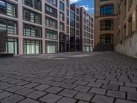 a brick courtyard has steps leading up to it, and a blue umbrella is on the ground