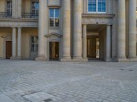 a courtyard with a building on the other side and a large white building with many windows