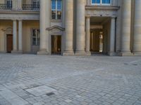 a courtyard with a building on the other side and a large white building with many windows