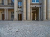 a courtyard with a building on the other side and a large white building with many windows