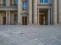 a courtyard with a building on the other side and a large white building with many windows