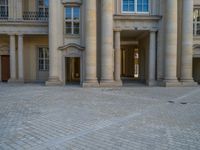 a courtyard with a building on the other side and a large white building with many windows