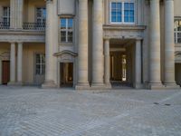 a courtyard with a building on the other side and a large white building with many windows