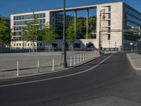 a street light next to an empty road in front of a building with a traffic light on top of it