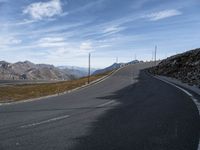 a deserted road leads to mountains in the distance and blue sky is visible in the distance