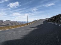 a deserted road leads to mountains in the distance and blue sky is visible in the distance