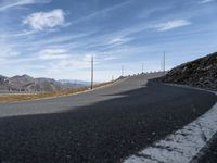 a deserted road leads to mountains in the distance and blue sky is visible in the distance