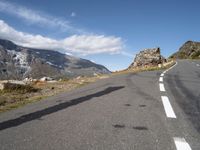 a man on a skateboard is riding on the road and mountain on the other side