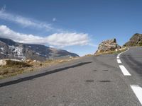 a man on a skateboard is riding on the road and mountain on the other side