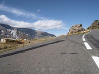 a man on a skateboard is riding on the road and mountain on the other side