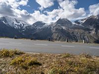 a bike is parked in the mountains by the side of the road with snow capped peaks