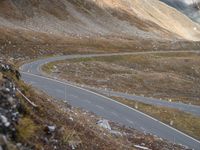 a road near mountains that has a car driving down it, with cloudy skies overhead