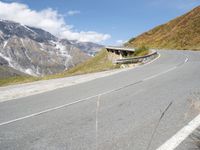 a motorcycle parked on a country road near snow - capped mountains with snowcapped summits