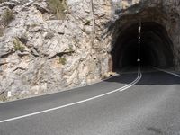 a large rock wall along a roadway with a tunnel at the end of it that is very steep, not much steep