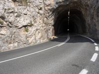 a large rock wall along a roadway with a tunnel at the end of it that is very steep, not much steep