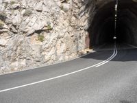 a large rock wall along a roadway with a tunnel at the end of it that is very steep, not much steep