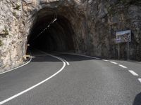 a large rock wall along a roadway with a tunnel at the end of it that is very steep, not much steep