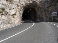 a large rock wall along a roadway with a tunnel at the end of it that is very steep, not much steep