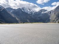 a person is on their cell phone and is running on an asphalt surface with a mountain range in the background